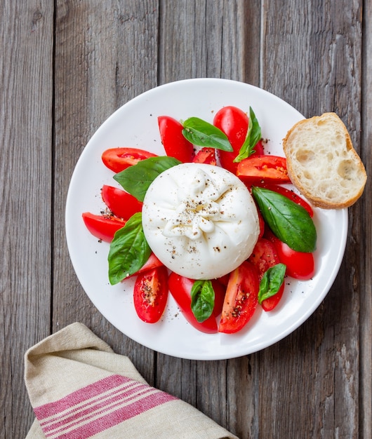 Queijo burrata italiano com tomate e manjericão. Salada. Alimentação saudável. Comida vegetariana.