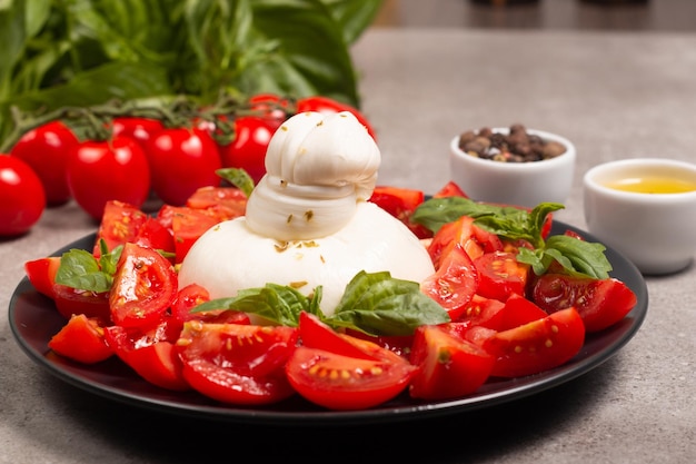 Foto queijo burrata tradicional italiano com salada de delicioso tomate cereja, folhas de manjericão e azeite