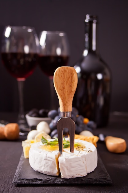 Foto queijo camembert brie no quadro, dois copos e garrafa de vinho tinto