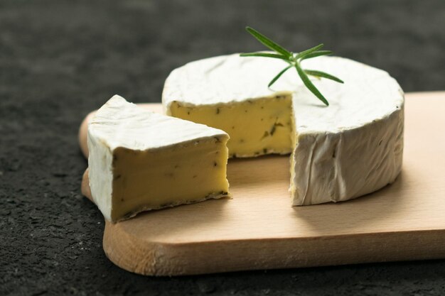 Queijo camembert com verdes decorados com um raminho de alecrim em uma placa de madeira