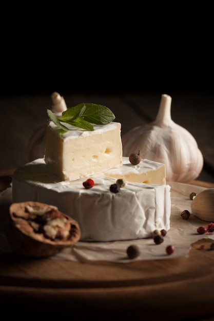 Queijo camembert e brie em de madeira com tomates, alface e alho. Comida italiana. Lacticínios.