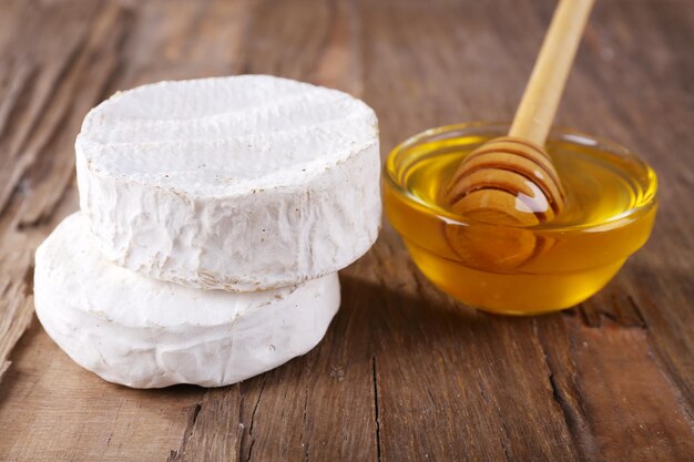 Foto queijo camembert e mel na tigela de vidro com fundo de madeira