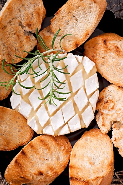 Queijo Camembert e um raminho de alecrim em uma mesa de madeira