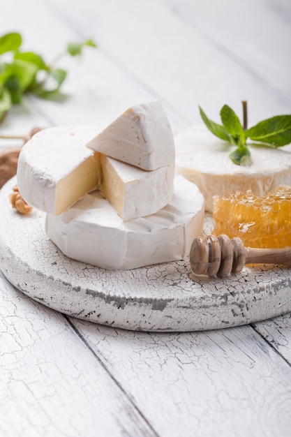 Queijo Camembert em uma placa de madeira com nozes, mel e hortelã. Gourment italiano, francês