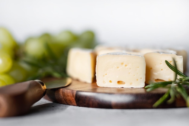 Queijo camembert em uma placa de madeira no contexto das uvas