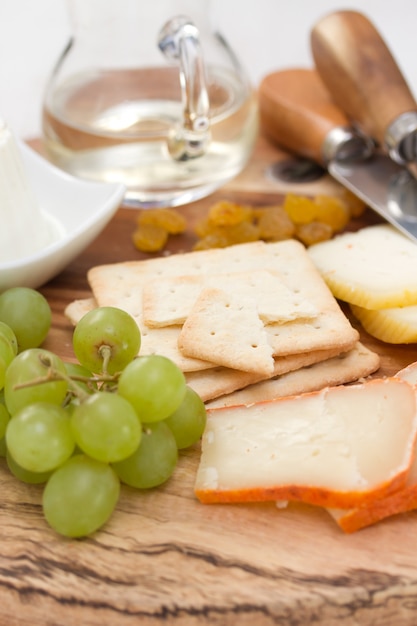 Queijo com biscoitos, uvas e vinho branco