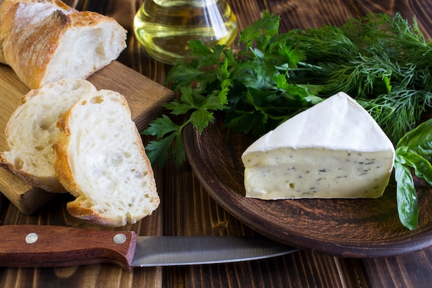 Queijo com ervas e baguete no fundo de madeira