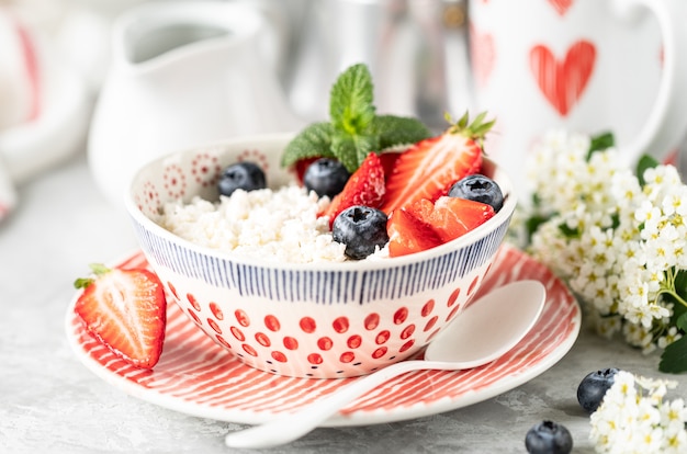 Queijo Cottage com frutas, geléia, morangos frescos e uma xícara de café com creme no café da manhã.