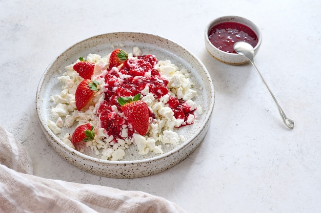 Queijo cottage com geléia e morangos em um prato perto de confiture de framboesa