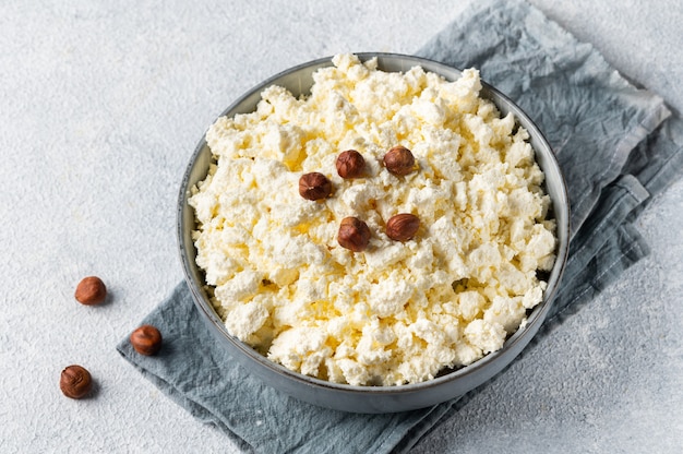 Queijo cottage e avelã em uma tigela cinza sobre fundo branco. Café da manhã saudável. Conceito de comida saudável.