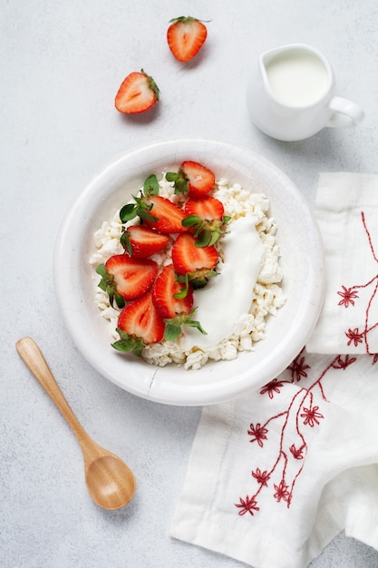Queijo cottage, requeijão com morangos em uma tigela, laticínios ogrânicos caseiros. Produtos lácteos saudáveis, ricos em Cálcio e Proteínas.