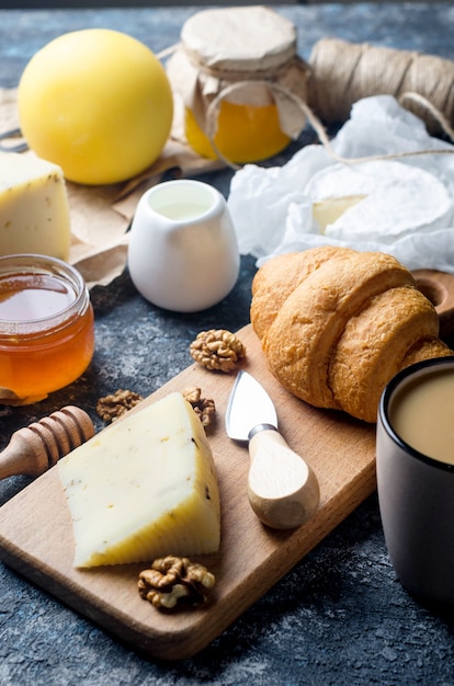 Queijo de diversos pedaços caseiros com mel, frutas, biscoitos e nozes na mesa. Produtos lácteos frescos, alimentos orgânicos saudáveis. Aperitivo delicioso.