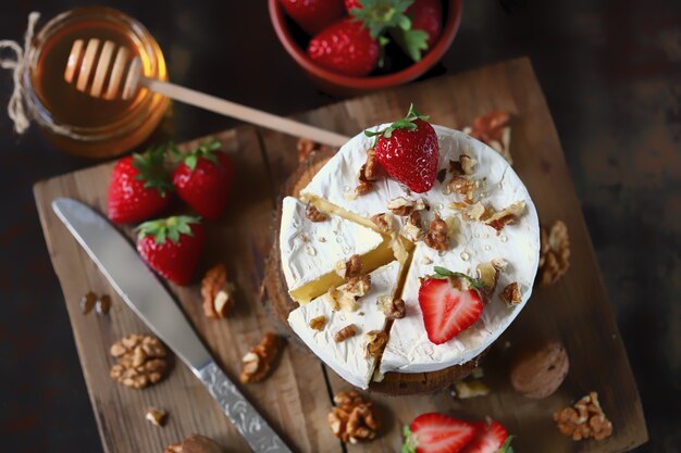 Queijo delicioso camembert com mel, nozes e morangos