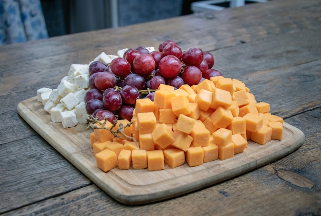 Queijo e uvas em uma tábua de madeira