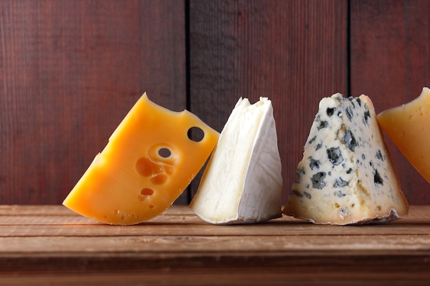 Queijo em tábuas de madeira. Camembert, queijo amarelo duro, dorblu em tábuas de madeira.