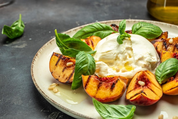 Queijo macio Burrata e pêssegos grelhados com manjericão e pinhões regados com mel Fundo da receita de alimentos Close-up