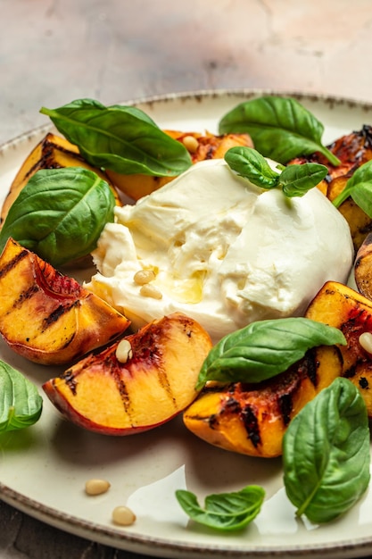 Queijo macio Burrata e pêssegos grelhados com manjericão e pinhões regados com mel Fundo da receita de alimentos Close-up