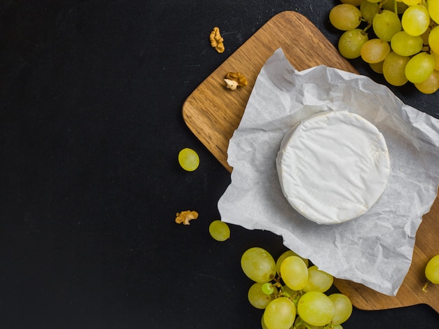 Queijo macio. Camembert e uvas em uma madeira com nozes