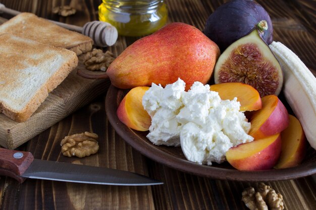 Queijo macio e frutas na placa o fundo de madeira