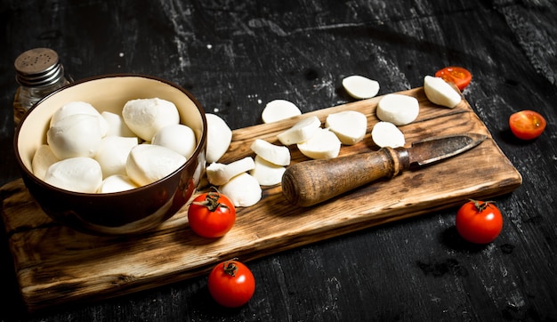 Queijo mussarela com uma faca velha e tomates.