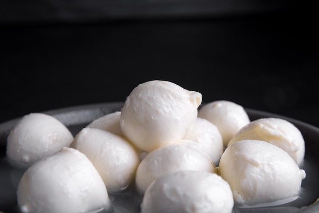 Queijo mussarela italiano tradicional e manjericão em prato de cerâmica áspero e superfície preta