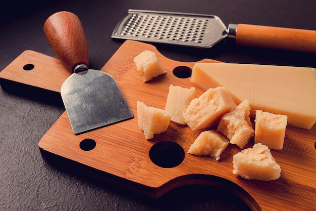 Queijo parmesão duro em uma tábua de corte faca de queijo ralador vista superior sem pessoas