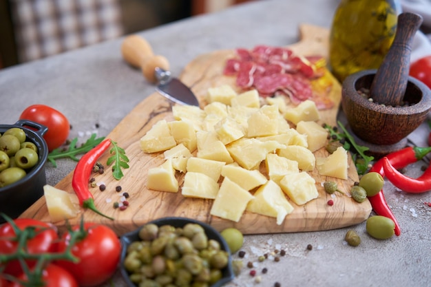 Queijo parmesão picado e legumes na mesa cinza na cozinha doméstica