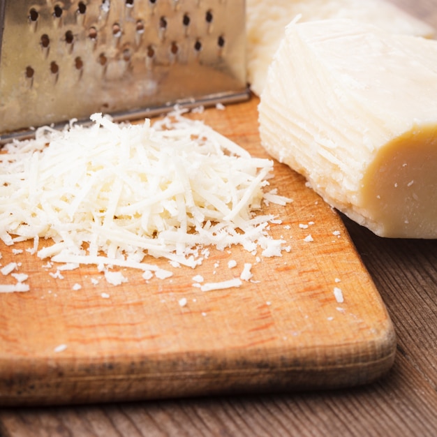 Foto queijo parmesão ralado com ralador em uma mesa