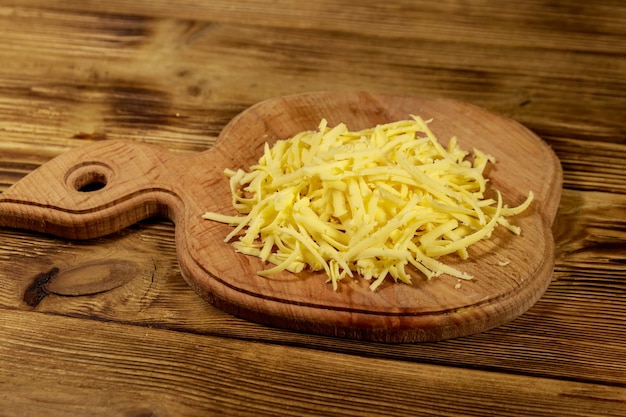 Queijo ralado na tábua na mesa de madeira