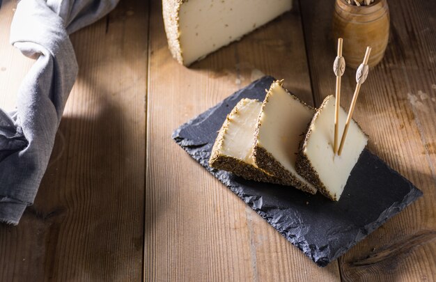 Queijo semi-curado com uma fina camada de ervas aromáticas.