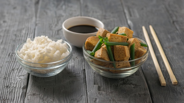 Queijo tofu grelhado com cebolinha, arroz e molho de soja em uma mesa de madeira. aperitivo de queijo grelhado.