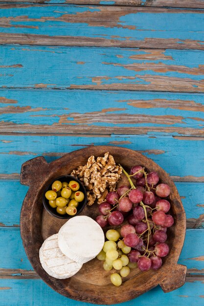 Queijo, uvas, azeitonas e nozes em uma tigela de madeira