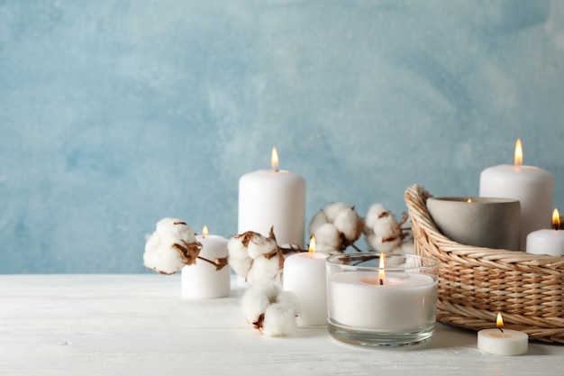 Queima de velas, cesta e algodão na mesa de madeira branca