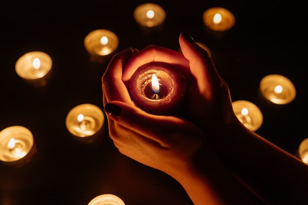 Queima de velas. vela em mãos femininas. muitas velas acesas à noite. muitas chamas de velas brilhando.