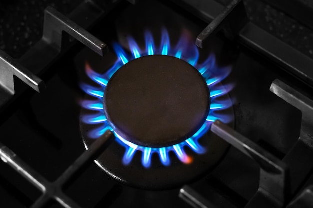 Queimador de gás com uma chama azul em um fogão de cozinha preto com uma grelha de castiron vista superior crise de gás de foco suave seletivo