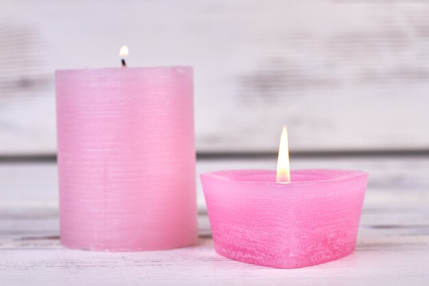 Queimando velas de cera rosa em fundo branco de madeira