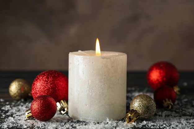 Queimando velas e bolas de Natal em madeira com neve, close-up Queimando velas e bolas de Natal em madeira com neve, close-up