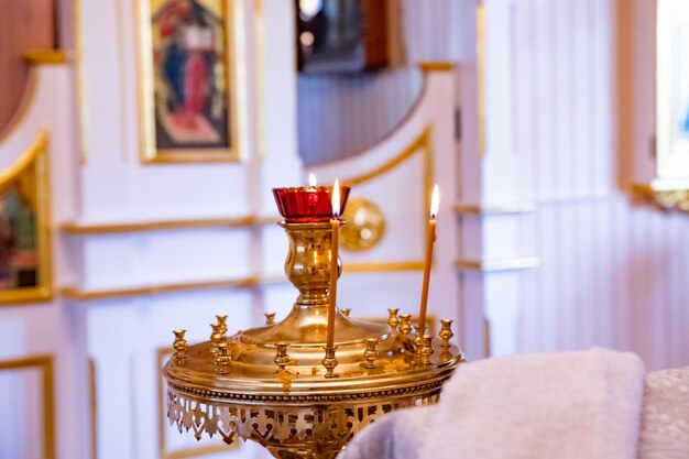 Queimando velas nas velas de cera do templo iluminadas contra o fundo de uma cruz com um crucifixo chri