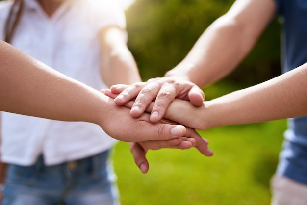 Quem é a melhor família do mundo Close de um grupo de pessoas formando um amontoado com as mãos enquanto estão do lado de fora em um parque durante o dia