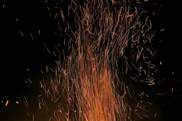 Quema brillante Contraste de chispas Fuego de leona girando hacia arriba contra el fondo negro Fuego de campamento nocturno