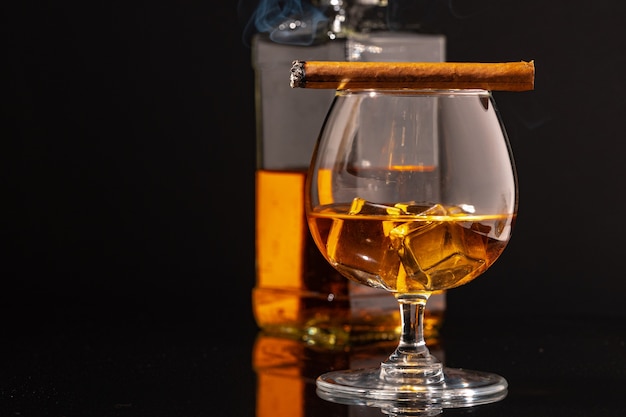 Quema de cigarros y vaso de whisky en el cuadro negro