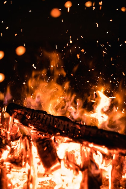 Quema de leña en un fuego con chispas en la oscuridad Llama naranja brillante