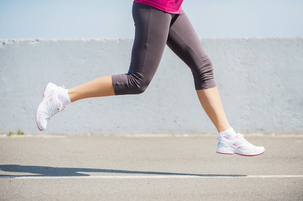 Quema las millas de distancia. Vista lateral de la imagen de primer plano de la mujer corriendo al aire libre