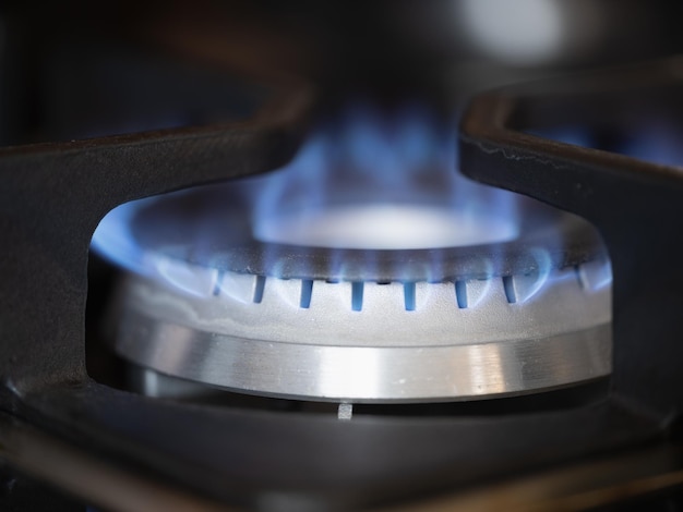 Quemador de gas en la estufa con fuego azul en el primer plano de la casa