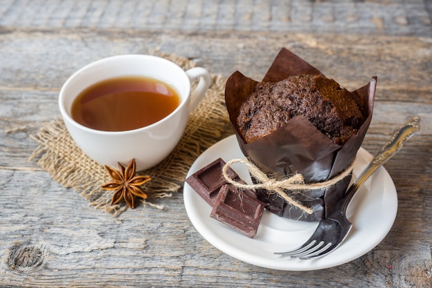 Queque do chocolate e uma xícara de café em uma superfície de madeira.