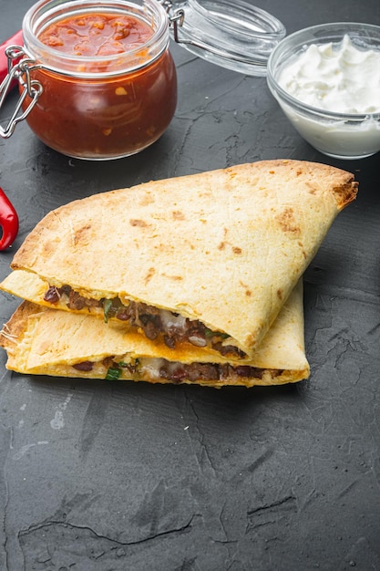 Quesadilla com frango e molho, sobre fundo preto