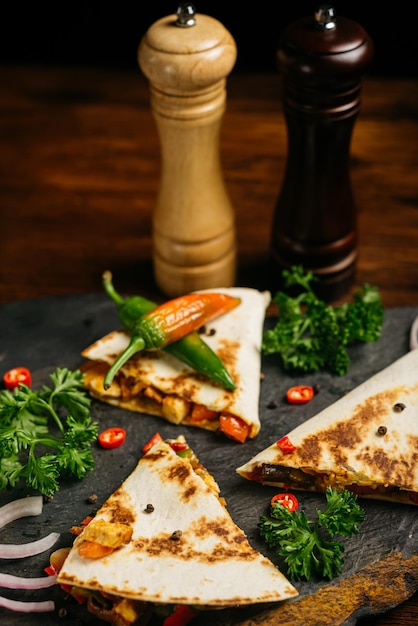 Quesadilla de frango com folhas de salsa crespa e pimenta e duas garrafas de molho picante