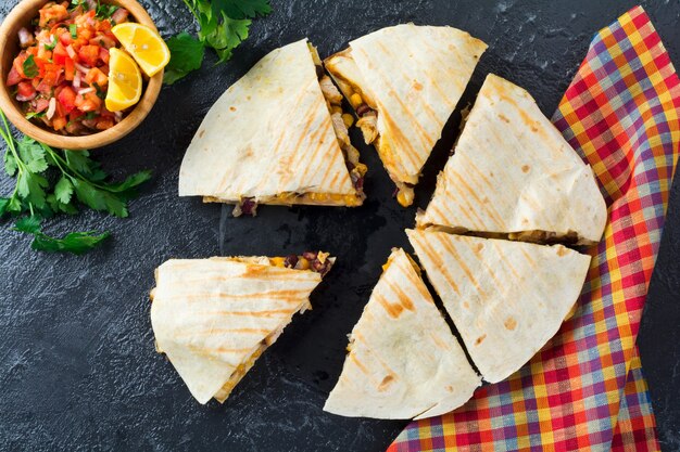 Quesadilla mexicana com frango, milho, feijão vermelho, queijo e pimentão e salsa. Foco seletivo. Vista superior.