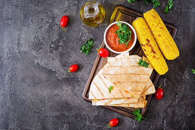 Quesadilla mexicana envuelta con pollo, maíz y pimiento dulce y salsa de tomate. Vista superior. Lay Flat