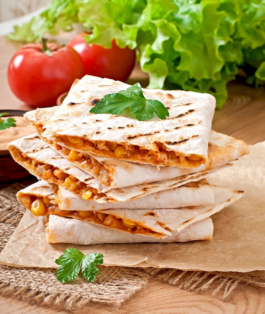 Quesadilla mexicana en rodajas con verduras y salsas sobre la mesa